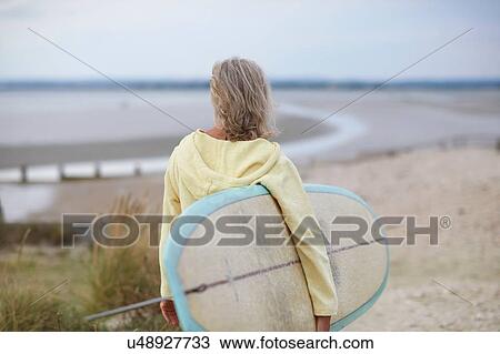 Senior woman walking towards beach, carrying surfboard, rear view View Large Photo Image Stock Image - Senior woman walking towards beach, carrying surfboard, rear view. Fotosearch