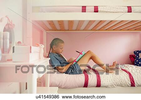 Side view of girl sitting on bunkbed writing in notebook View Large Photo Image Stock Photograph - Side view of girl sitting on bunkbed writing in notebook. Fotosearch