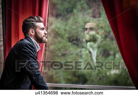Side view of mid adult man wearing suit looking out of window View Large Photo Image Stock Photo - Side view of mid adult man wearing suit looking out of window. Fotosearch