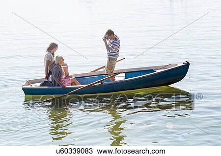 Side view of young man in boat on lake photographing women View Large Photo Image Stock Image - Side view of young man in boat on lake photographing women. Fotosearch