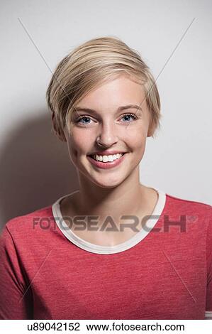 Stock Image - Studio portrait of happy young woman with short blond hair. Fotosearch