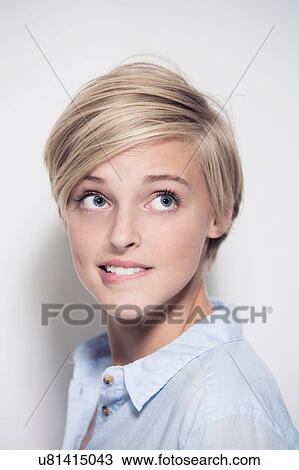 Stock Image - Studio portrait of young woman biting her lip. Fotosearch