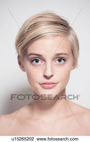 Stock Image - Studio portrait of young woman with short blond hair and blue eyes. Fotosearch