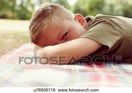 Surface level view of boy lying on picnic blanket, face obscured looking at camera View Large Photo Image Stock Photograph - Surface level view of boy lying on picnic blanket, face obscured looking at camera. Fotosearch