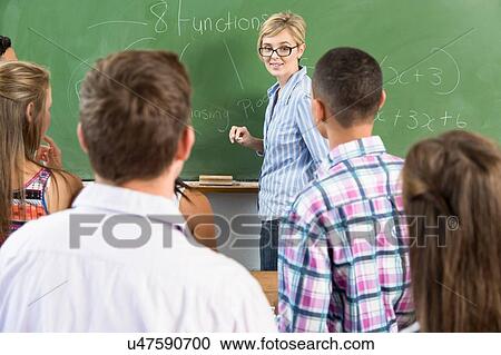 Stock Image - Teacher addressing students in classroom. Fotosearch