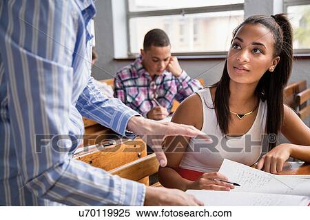 Stock Photography - Teacher helping female student in classroom. Fotosearch