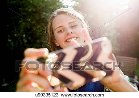 Teenage girl taking smartphone selfie in park View Large Photo Image Stock Image - Teenage girl taking smartphone selfie in park. Fotosearch