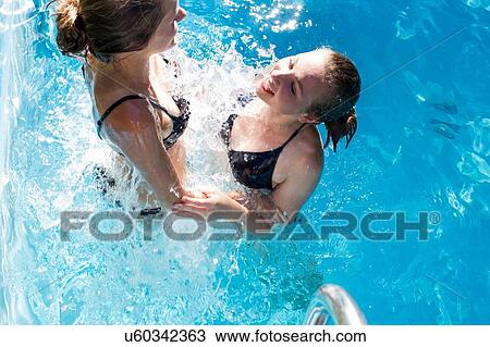 Teenage girls splashing in swimming pool View Large Photo Image Stock Image - Teenage girls splashing in swimming pool. Fotosearch