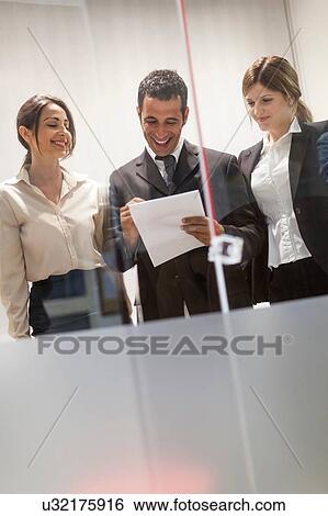 Three colleagues looking through documents in office View Large Photo Image Stock Photograph - Three colleagues looking through documents in office. Fotosearch