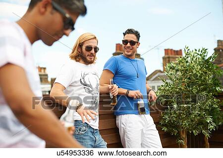 Three male friends drinking beer at rooftop barbecue View Large Photo Image Stock Photograph - Three male friends drinking beer at rooftop barbecue. Fotosearch