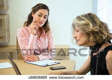 Two businesswomen brainstorming at boardroom table View Large Photo Image Stock Photo - Two businesswomen brainstorming at boardroom table. Fotosearch