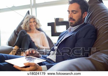 Stock Photo - Two designers relaxing on beanbag chairs in office. Fotosearch