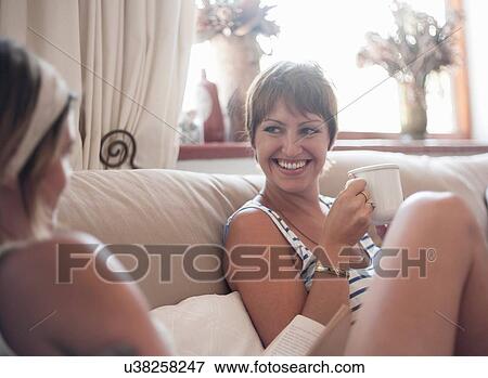 Two female friends, sitting on sofa, drinking tea View Large Photo Image Stock Photo - Two female friends, sitting on sofa, drinking tea. Fotosearch