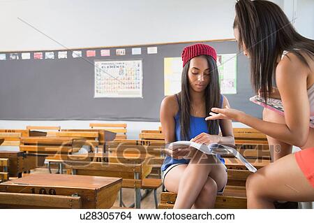 Two female students in empty classroom, talking View Large Photo Image Picture - Two female students in empty classroom, talking. Fotosearch