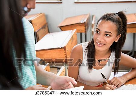 Two female students talking in classroom View Large Photo Image Stock Image - Two female students talking in classroom. Fotosearch