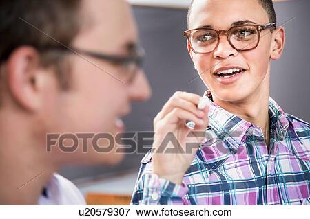 Two male students talking in classroom View Large Photo Image Stock Photo - Two male students talking in classroom. Fotosearch