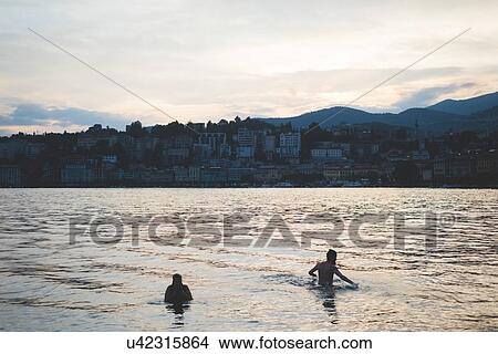Two silhouetted tourists swimming in Lake Lugano, Switzerland View Large Photo Image Picture - Two silhouetted tourists swimming in Lake Lugano, Switzerland. Fotosearch