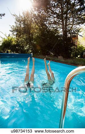 Two teenage girls diving into swimming pool View Large Photo Image Stock Image - Two teenage girls diving into swimming pool. Fotosearch