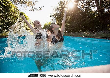 Two teenage girls jumping with arms raised in swimming pool View Large Photo Image Stock Photograph - Two teenage girls jumping with arms raised in swimming pool. Fotosearch