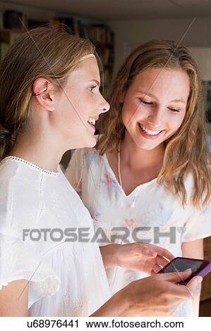 Stock Image - Two teenage girls reading smartphone texts. Fotosearch