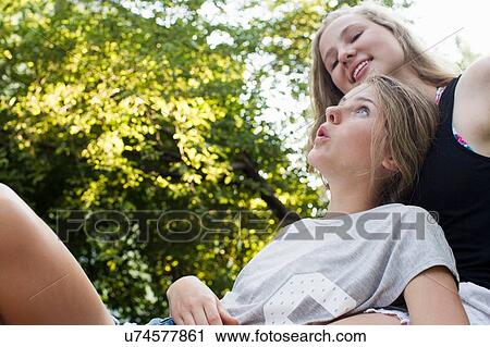 Two teenage girls reclining in garden View Large Photo Image Stock Image - Two teenage girls reclining in garden. Fotosearch