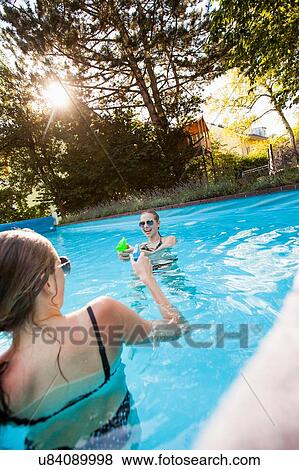 Two teenage girls squirting water pistols in swimming pool View Large Photo Image Stock Photo - Two teenage girls squirting water pistols in swimming pool. Fotosearch