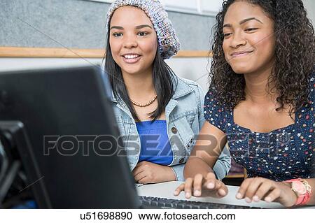 Stock Image - Two teenage girls typing in high school computer class. Fotosearch