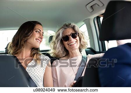 Two women chatting in back seat of car View Large Photo Image Stock Photo - Two women chatting in back seat of car. Fotosearch