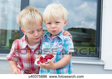 Two young brothers on patio eating a bowl of raspberries View Large Photo Image Stock Photograph - Two young brothers on patio eating a bowl of raspberries. Fotosearch