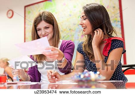 Picture - Two young women sitting together, studying. Fotosearch