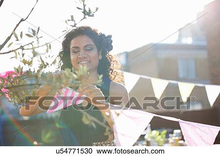 Woman hanging bunting for early evening party View Large Photo Image Stock Image - Woman hanging bunting for early evening party. Fotosearch