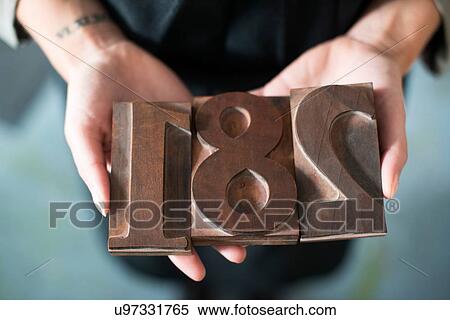 Stock Photography - Womans hands holding traditional letterpress numerals workshop. Fotosearch