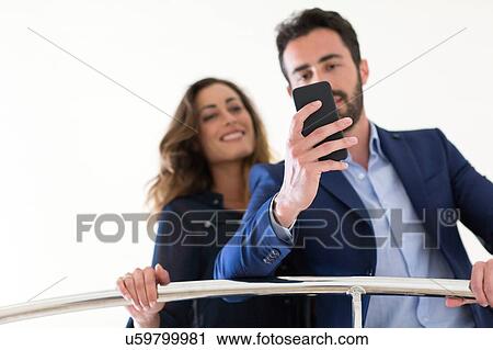 Stock Image - Young businessman and woman reading smartphone texts. Fotosearch