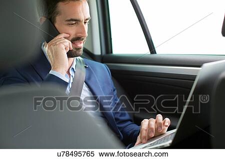 Young businessman chatting on smartphone in back seat of car View Large Photo Image Stock Photography - Young businessman chatting on smartphone in back seat of car. Fotosearch