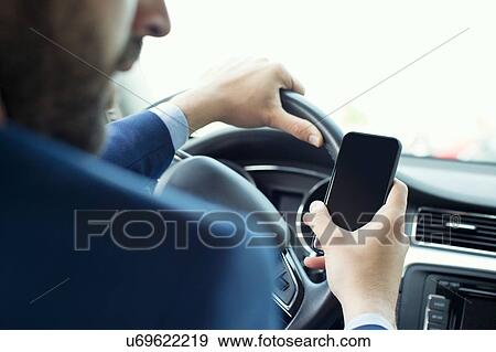 Young businessman reading smartphone text in car View Large Photo Image Stock Photo - Young businessman reading smartphone text in car. Fotosearch