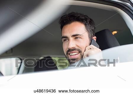 Young businessman talking on smartphone in car View Large Photo Image Stock Photograph - Young businessman talking on smartphone in car. Fotosearch