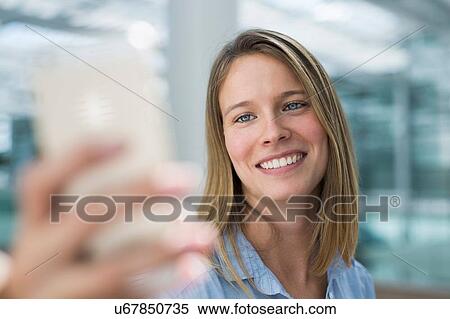 Stock Photography - Young businesswoman taking smartphone selfie. Fotosearch