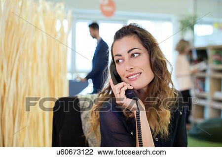 Young businesswoman talking on landline telephone in office View Large Photo Image Stock Image - Young businesswoman talking on landline telephone in office. Fotosearch