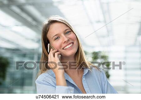 Young businesswoman talking on smartphone outside office View Large Photo Image Stock Image - Young businesswoman talking on smartphone outside office. Fotosearch