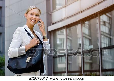 Young businesswoman talking on smartphone outside office View Large Photo Image Stock Photo - Young businesswoman talking on smartphone outside office. Fotosearch