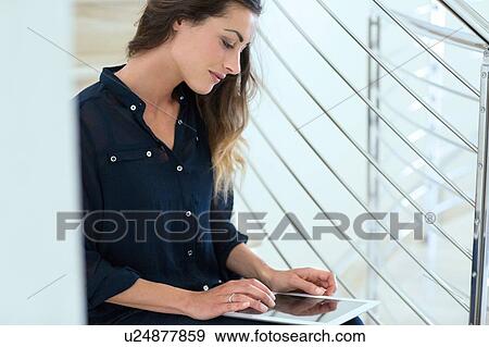 Stock Photo - Young businesswoman using digital tablet on office stairway. Fotosearch