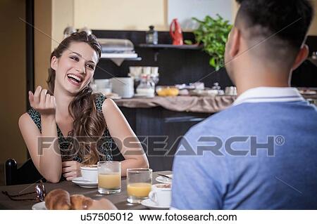 Young couple laughing over breakfast in hotel dining room View Large Photo Image Stock Image - Young couple laughing over breakfast in hotel dining room. Fotosearch