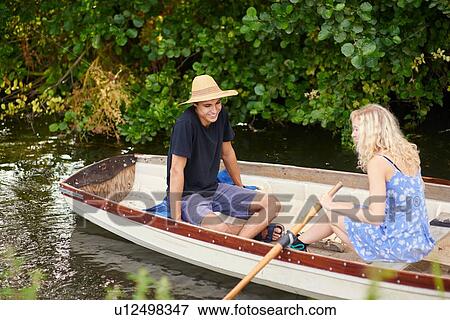 Stock Photo - Young couple rowing river rowing boat. Fotosearch