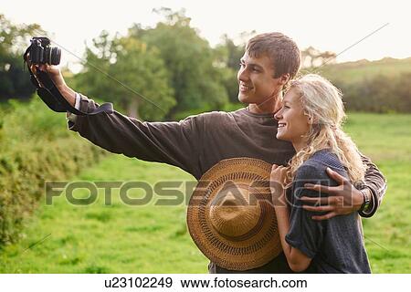 Young couple taking self portrait in rural field View Large Photo Image Stock Photo - Young couple taking self portrait in rural field. Fotosearch