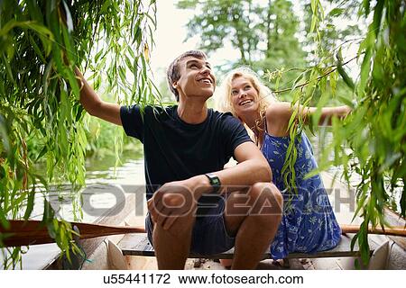 Young couple touching willow tree foliage from rowing boat on rural river View Large Photo Image Stock Image - Young couple touching willow tree foliage from rowing boat on rural river. Fotosearch