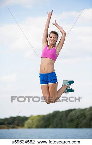 Young female runner jumping mid air at lakeside View Large Photo Image Stock Image - Young female runner jumping mid air at lakeside. Fotosearch