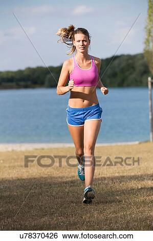 Young female runner running at lakeside View Large Photo Image Stock Photograph - Young female runner running at lakeside. Fotosearch