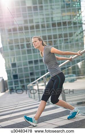 Stock Photo - Young female runner warming up in city. Fotosearch