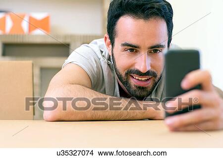Young male designer reading smartphone texts at boardroom table View Large Photo Image Picture - Young male designer reading smartphone texts at boardroom table. Fotosearch