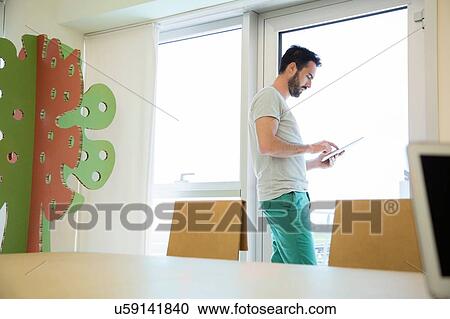 Young male designer using digital tablet touchscreen in office View Large Photo Image Stock Image - Young male designer using digital tablet touchscreen in office. Fotosearch